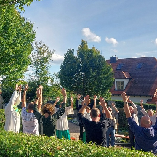 Auf dem Friedhof in Püssensheim stehen Menschen und hebe die Hände in die Höhe.
